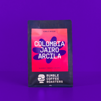 Bag of coffee beans with 'Colombia Jairo Arcila' on a purple background