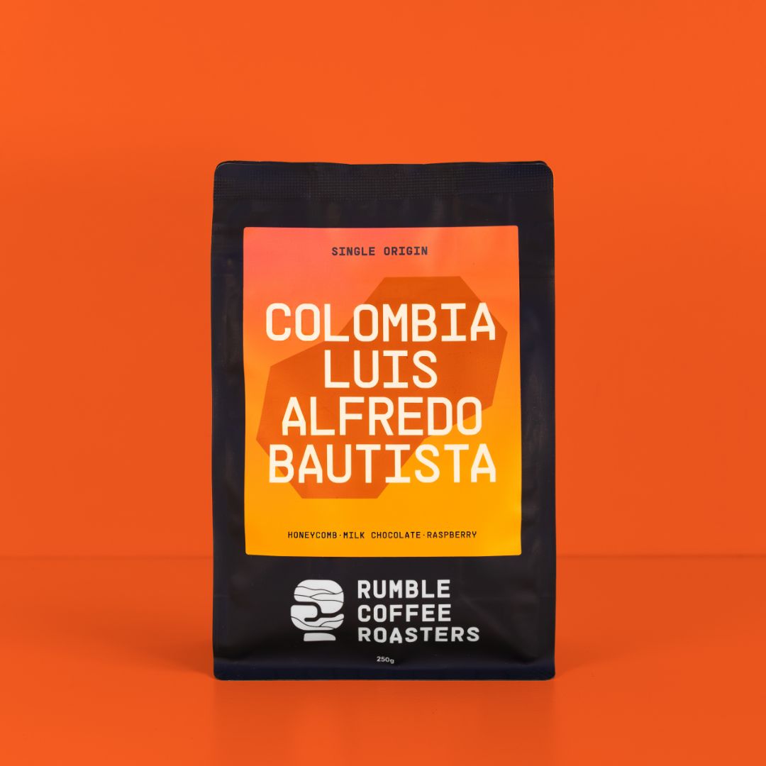 A 250g bag of Rumble Coffee Roasters Colombia Luis Alfredo Bautista coffee on a solid orange background.