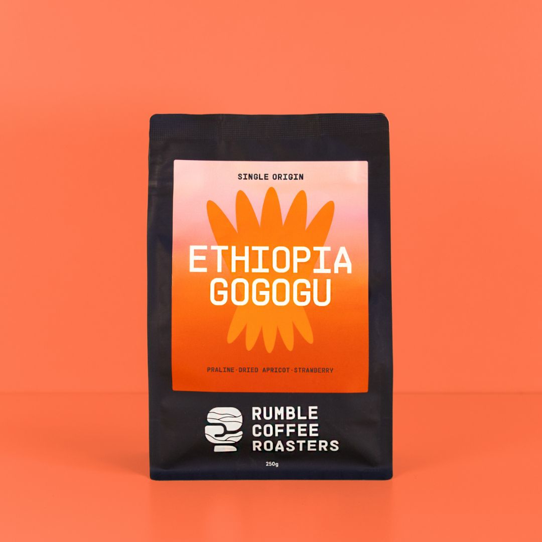 A 350g bag of Rumble Coffee Roasters Ethiopia Gogogu coffee, featuring a black bag with a prominent orange and pink label, set against a solid orange background.
