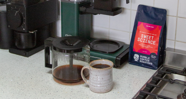 Coffee making setup with moccamaster, mug full of coffee, and a bag of Rumble Coffee Sweet Science filter blend.