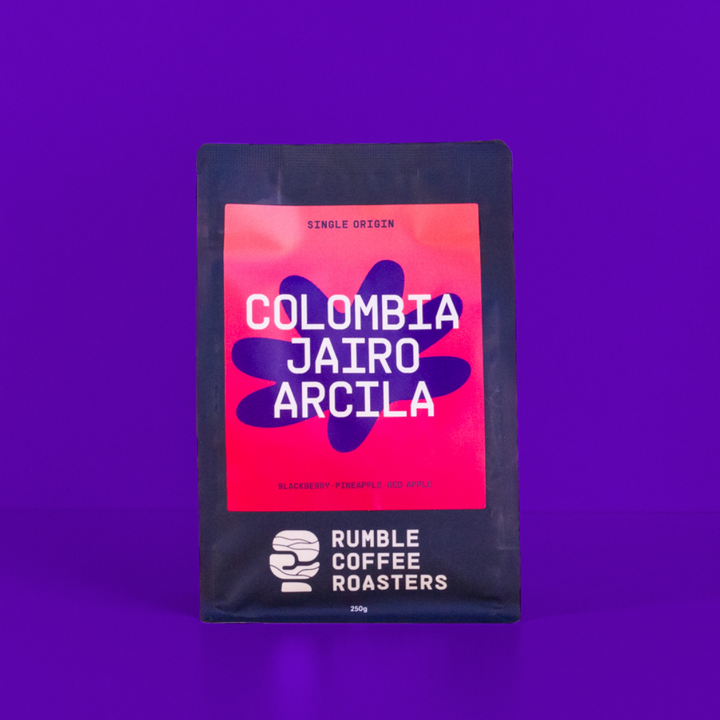 Bag of coffee beans with 'Colombia Jairo Arcila' on a purple background