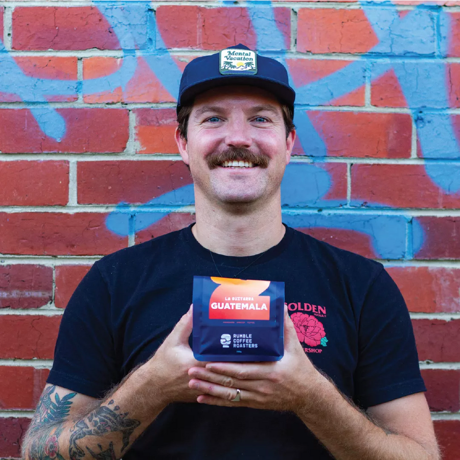 Luke holding a coffee bag of Rumble Coffees new single origin